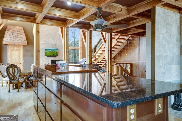 kitchen featuring dark stone countertops, ceiling fan, light hardwood / wood-style flooring, crown molding, and coffered ceiling