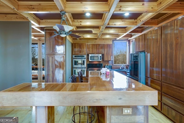 kitchen with stainless steel appliances, beam ceiling, coffered ceiling, and wooden walls