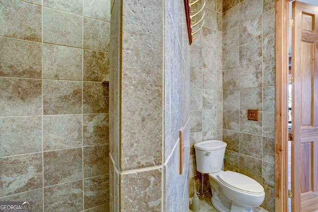 bathroom featuring tile walls and toilet