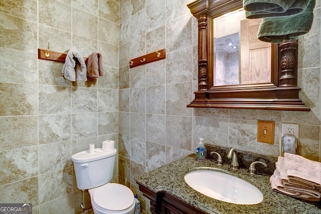 bathroom with toilet, tile walls, and vanity