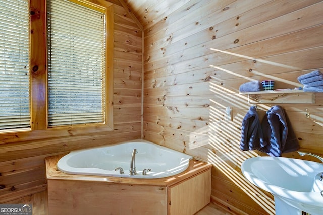 bathroom featuring sink, a washtub, and wood walls