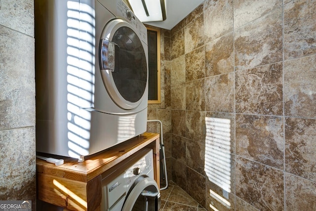 interior space with tile walls, dark tile patterned floors, and stacked washer and dryer