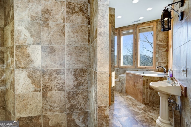 bathroom with tile walls and a relaxing tiled tub