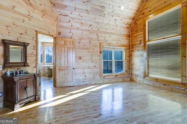 unfurnished room featuring light hardwood / wood-style floors, wood ceiling, and wooden walls