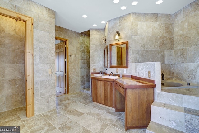 bathroom featuring tile walls, tiled tub, and vanity