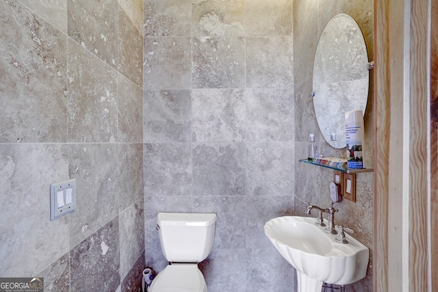 bathroom featuring toilet, tile walls, and sink