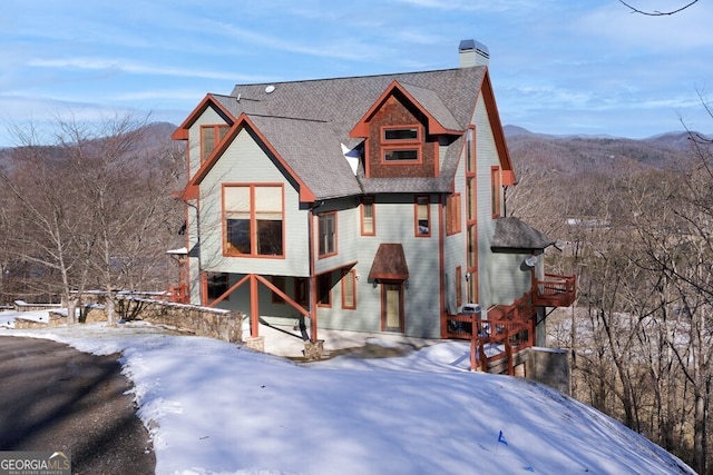 snow covered back of property featuring a mountain view