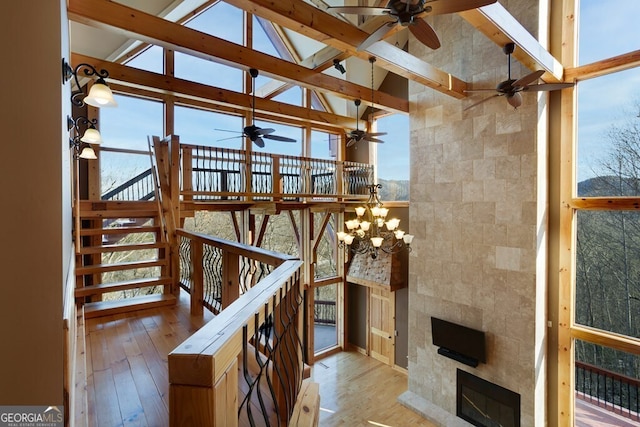 living room with high vaulted ceiling, a tile fireplace, a chandelier, and light hardwood / wood-style floors