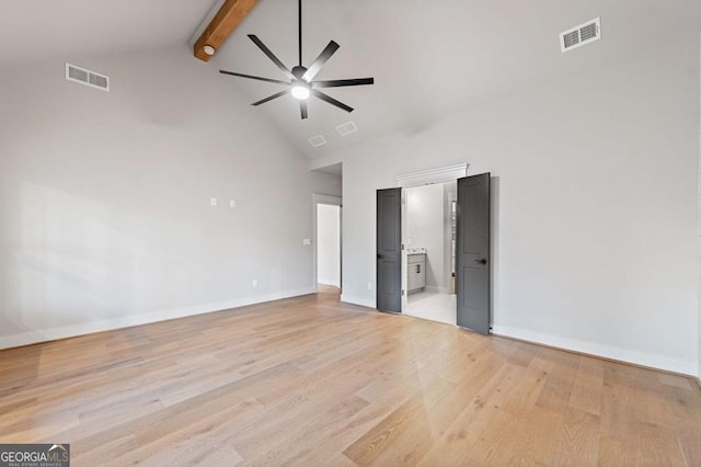 unfurnished bedroom with connected bathroom, beam ceiling, light wood-type flooring, and high vaulted ceiling