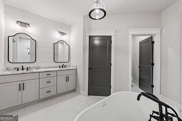 bathroom with toilet, a bath, and vanity