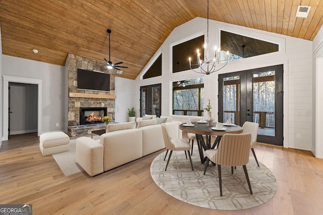 dining room featuring light hardwood / wood-style floors, a fireplace, french doors, high vaulted ceiling, and ceiling fan with notable chandelier