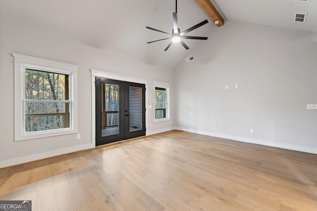 empty room with vaulted ceiling with beams, a healthy amount of sunlight, french doors, and ceiling fan