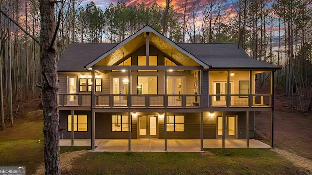 back house at dusk featuring a patio area and a balcony