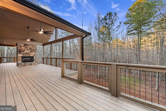 wooden terrace with ceiling fan and an outdoor stone fireplace