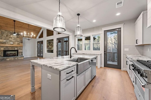 kitchen featuring pendant lighting, decorative backsplash, sink, wood ceiling, and an island with sink