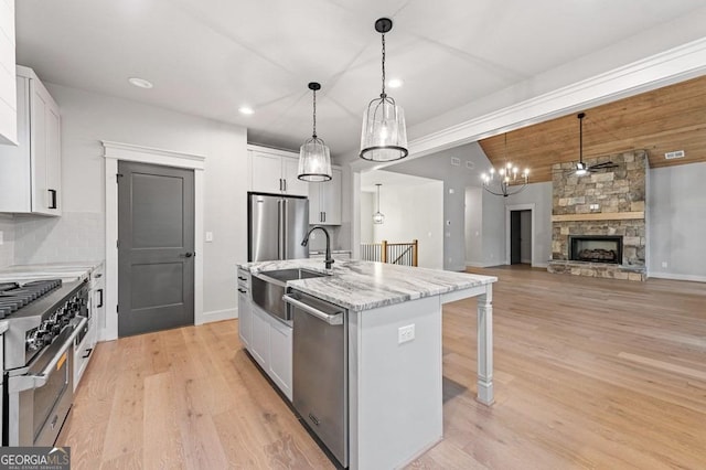 kitchen with pendant lighting, white cabinetry, a center island with sink, and high end appliances