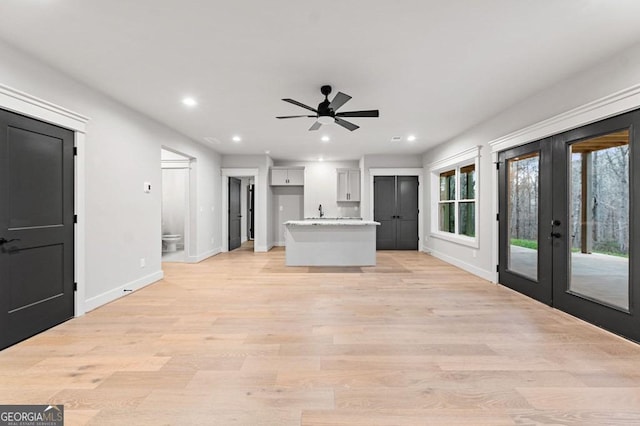 unfurnished living room with ceiling fan, french doors, and light hardwood / wood-style floors