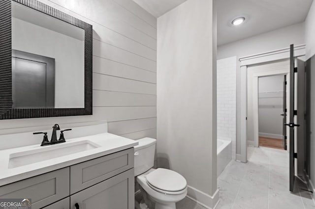 full bathroom with toilet,  shower combination, wood walls, and vanity