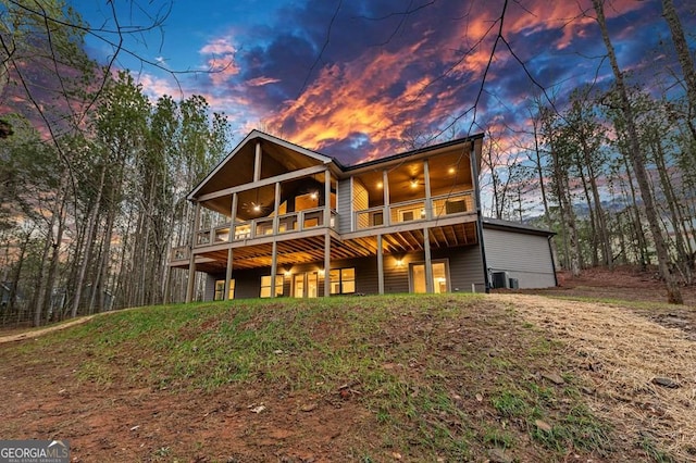 back house at dusk featuring ceiling fan and a balcony