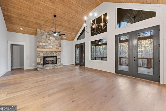 unfurnished living room with high vaulted ceiling, french doors, a stone fireplace, and hardwood / wood-style flooring