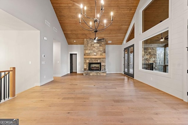 unfurnished living room with light hardwood / wood-style floors, ceiling fan with notable chandelier, high vaulted ceiling, and a fireplace