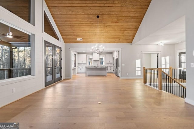 unfurnished dining area featuring wood ceiling, ceiling fan with notable chandelier, and light hardwood / wood-style flooring