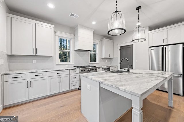 kitchen featuring white cabinetry, an island with sink, custom range hood, high end appliances, and sink