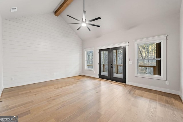 empty room featuring ceiling fan, beamed ceiling, french doors, and light wood-type flooring