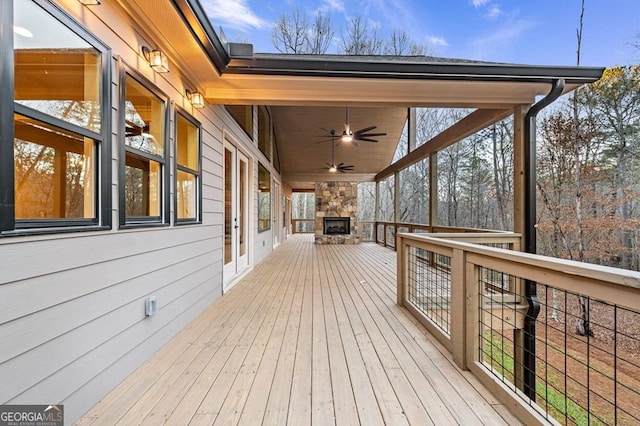 wooden terrace featuring ceiling fan and an outdoor stone fireplace