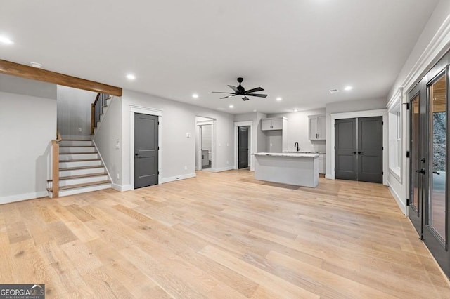 unfurnished living room featuring ceiling fan, light hardwood / wood-style flooring, and sink