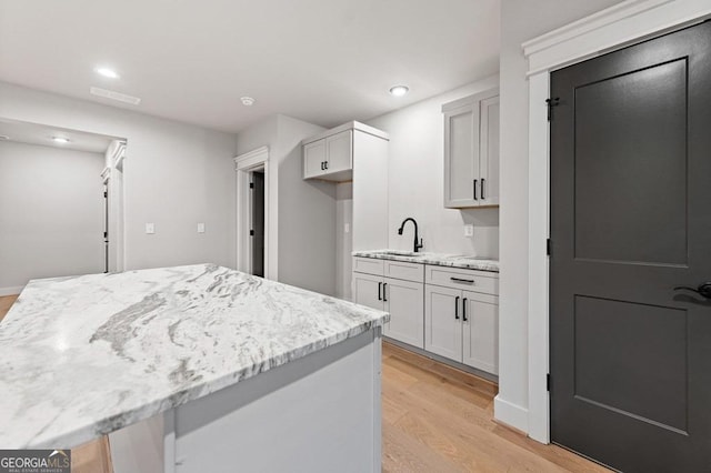 kitchen featuring light stone counters, sink, and light hardwood / wood-style floors