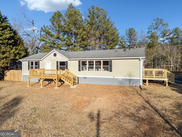 rear view of house featuring a wooden deck and a yard