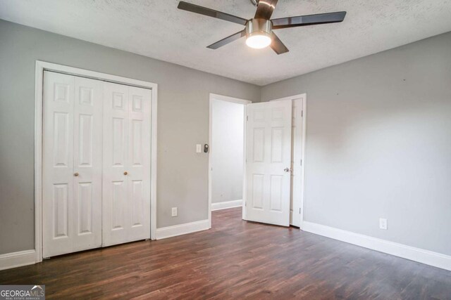 unfurnished bedroom with a textured ceiling, ceiling fan, dark hardwood / wood-style flooring, and a closet