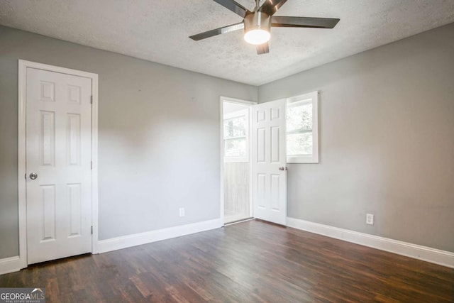 empty room with a textured ceiling, ceiling fan, and dark hardwood / wood-style floors