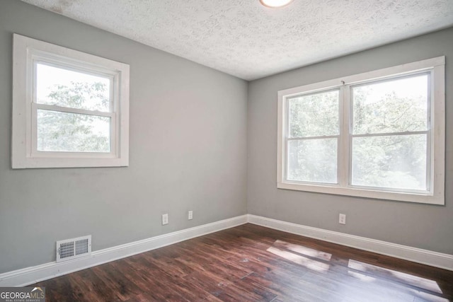 empty room with a textured ceiling and dark hardwood / wood-style flooring