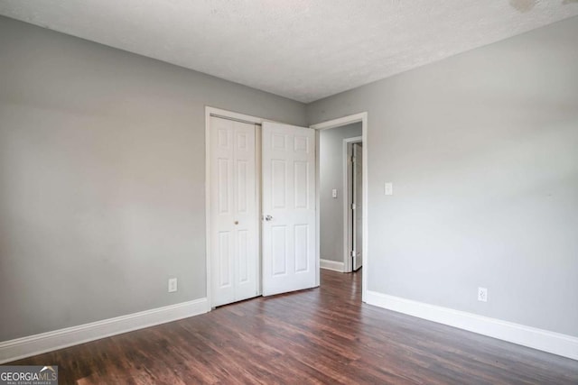 unfurnished bedroom featuring a textured ceiling and dark hardwood / wood-style floors