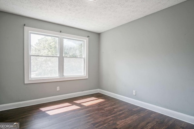 spare room featuring dark wood-type flooring and a textured ceiling