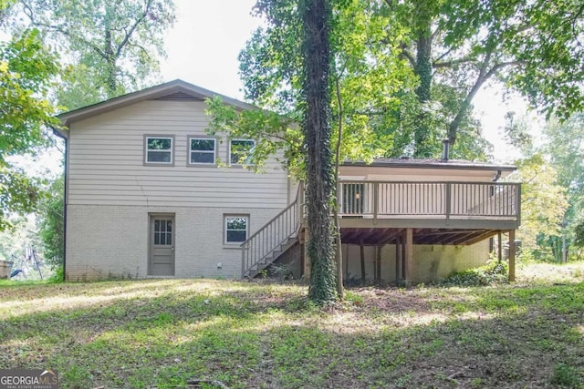 back of house featuring a lawn and a wooden deck