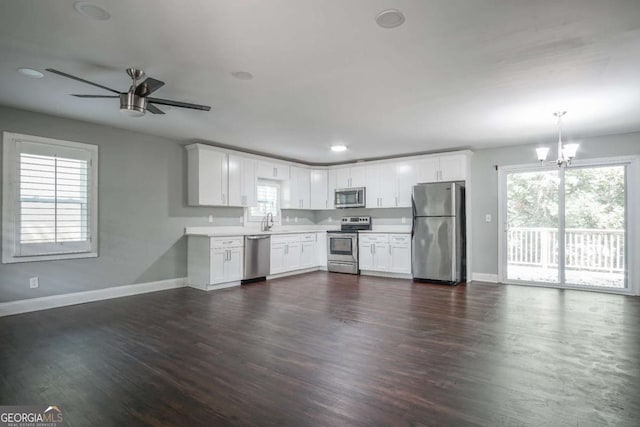 kitchen with ceiling fan with notable chandelier, appliances with stainless steel finishes, white cabinetry, sink, and hanging light fixtures