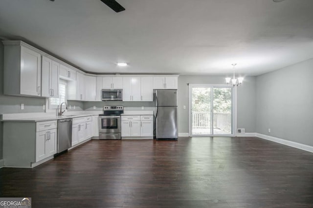 kitchen featuring decorative light fixtures, white cabinetry, stainless steel appliances, sink, and a chandelier