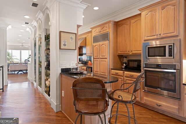 kitchen with ceiling fan, dark hardwood / wood-style floors, ornamental molding, and built in appliances