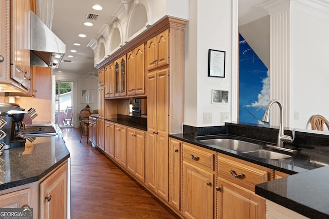 kitchen featuring dark hardwood / wood-style floors, dark stone countertops, range hood, ornamental molding, and sink