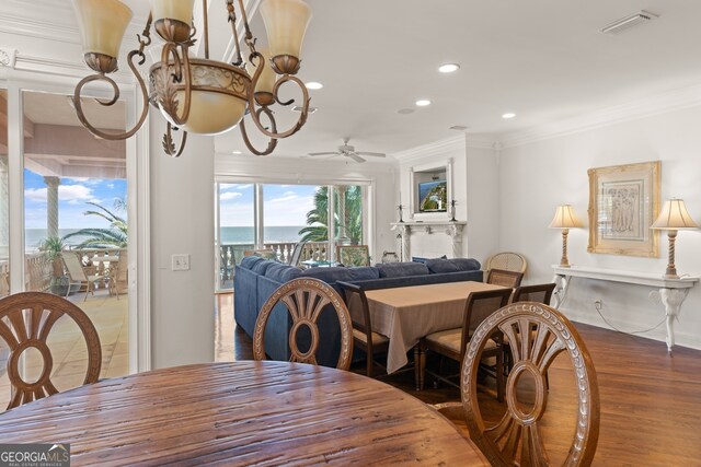 dining space with ceiling fan, ornamental molding, a water view, and hardwood / wood-style floors