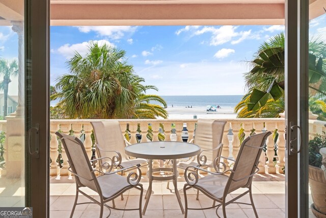 balcony with a water view and a view of the beach
