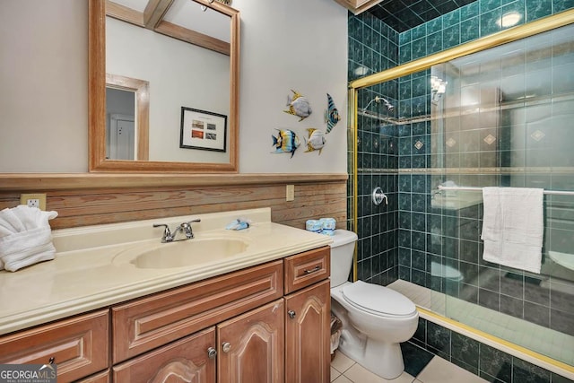 bathroom featuring toilet, vanity, tile patterned floors, wooden walls, and a shower with shower door