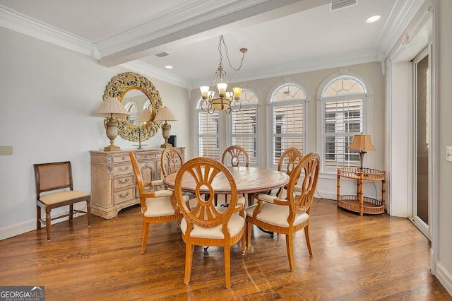 dining area with hardwood / wood-style floors, crown molding, and a chandelier