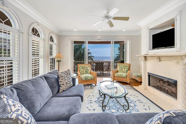 living room with ceiling fan, wood-type flooring, a fireplace, and ornamental molding