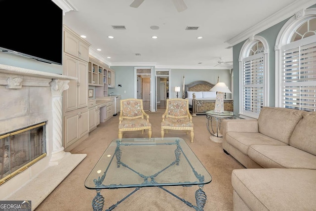living room with a premium fireplace, ceiling fan, crown molding, and light carpet
