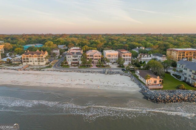 aerial view at dusk featuring a view of the beach and a water view