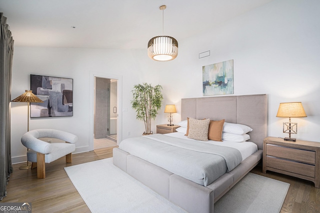 bedroom with wood-type flooring and connected bathroom